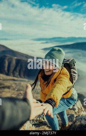 Persone che si aiutano a camminare su una montagna all'alba. Foto Stock
