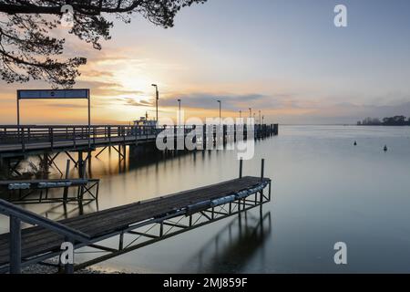 Gstadt am Chiemsee, Germania - 13 ottobre 2022: Alba sul porto e molo a Gstadt am Chiemsee (traduzione del cartello: Partenza in direzione W Foto Stock