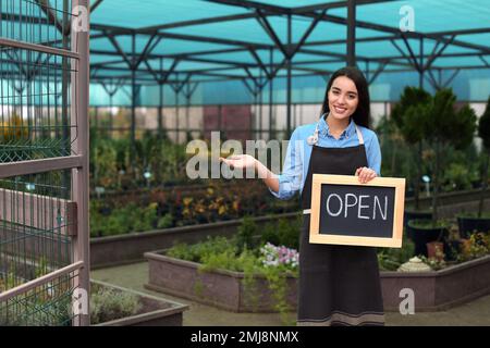 Titolare di un'azienda femminile che detiene IL segno APERTO in serra. Spazio per il testo Foto Stock