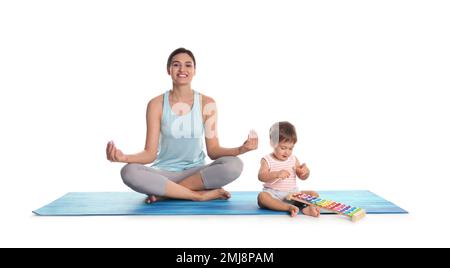 Giovane donna meditando mentre suo figlio gioca con il giocattolo xilofono isolato su bianco Foto Stock