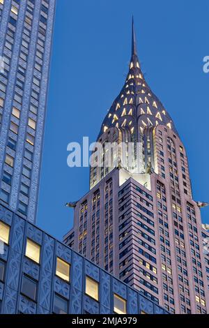 La corona iconica del Chrysler Building, incorniciata dal Socony-Mobil Building rivestito in acciaio inossidabile, cambia da grigio a oro alla luce dell'alba. Foto Stock