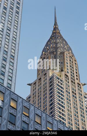 La corona iconica del Chrysler Building, incorniciata dal Socony-Mobil Building rivestito in acciaio inossidabile, cambia da grigio a oro alla luce dell'alba. Foto Stock