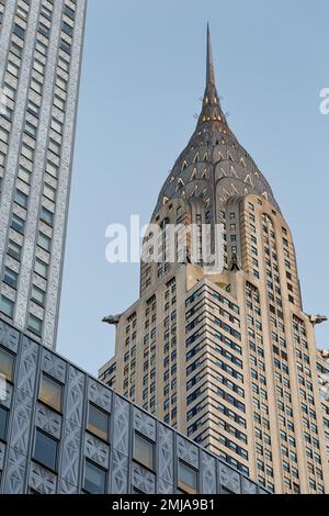 La corona iconica del Chrysler Building, incorniciata dal Socony-Mobil Building rivestito in acciaio inossidabile, cambia da grigio a oro alla luce dell'alba. Foto Stock