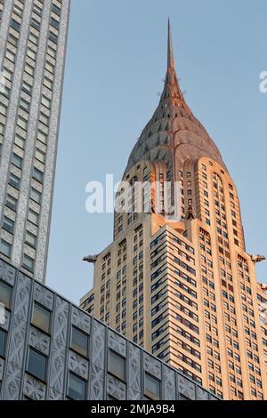 La corona iconica del Chrysler Building, incorniciata dal Socony-Mobil Building rivestito in acciaio inossidabile, cambia da grigio a oro alla luce dell'alba. Foto Stock