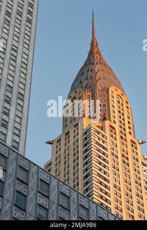 La corona iconica del Chrysler Building, incorniciata dal Socony-Mobil Building rivestito in acciaio inossidabile, cambia da grigio a oro alla luce dell'alba. Foto Stock