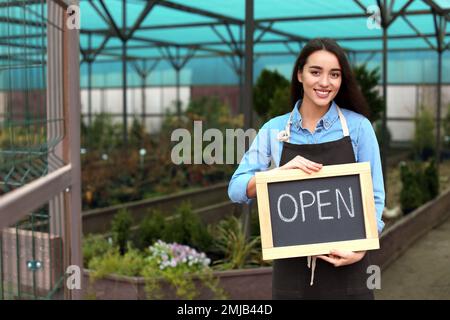 Titolare di un'azienda femminile che detiene IL segno APERTO in serra. Spazio per il testo Foto Stock