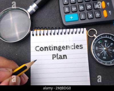 Hamd tenendo matita wriiten sul notebook con la parola contingenze piano. Concetto aziendale. Foto Stock