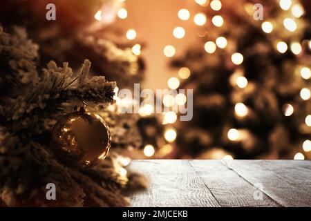 Bellissimo albero di Natale e superficie di legno su sfondo sfocato Foto Stock