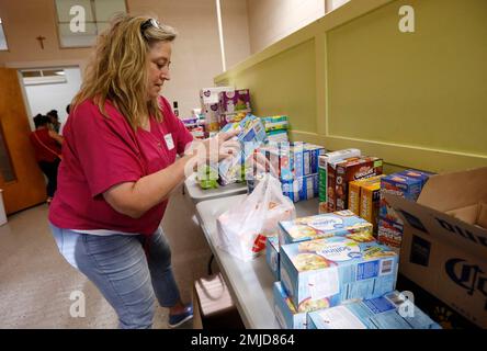 St. Joseph Catholic Church parishioner Gayle Price of Madison, stacks boxes of crackers in a storage room at the old school formerly used by Sacred Heart Catholic Church, Friday, Aug. 9. 2019 in Canton, Miss. Rice, beans, canned meats, diapers and other sundry items are being collected to assist families affected by the immigration raids of several food processing plants, including one in Canton. (AP Photo/Rogelio V. Solis)