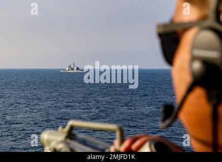 TAIWAN STRAIT (28 agosto 2022) Seaman Carlos Torres, di Houston, Texas, ricerca contatti superficiali sull'ala del ponte dell'incrociatore missilistico guidato di classe Ticonderoga USS Chancellorsville (CG 62) mentre transita lungo USS Antietam (CG 54) nello stretto di Taiwan durante un transito di routine vicino alle navi PLA(N). Chancellorsville è schierata in avanti nell'area delle operazioni della flotta degli Stati Uniti 7th a sostegno di un libero e aperto Indo-Pacific. Foto Stock