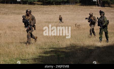 STATI UNITI Marines assegnato alla squadra di atterraggio del battaglione 2/6, 22nd unità di spedizione marina (MEU), E soldati svedesi assegnati a 5th Company, South Scania Regiment P7, corrono verso un obiettivo durante un esercizio di raid a Ravlunda, Svezia, 28 agosto 2022. Il Kearsarge Amphibious Ready Group e 22nd MEU, sotto il comando e il controllo della Task Force 61/2, è in programma uno schieramento negli Stati Uniti Naval Forces Europe area of Operations, impiegato dagli Stati Uniti Sesta flotta per difendere gli interessi degli Stati Uniti, alleati e partner. Foto Stock