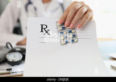 Il medico femminile mostra in bianco carta da prescrizione e pillole mediche. Foto Stock