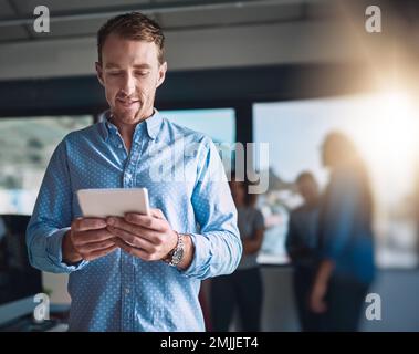 Focalizzato sull'attività. un bel giovane designer che utilizza il suo tablet digitale in ufficio. Foto Stock