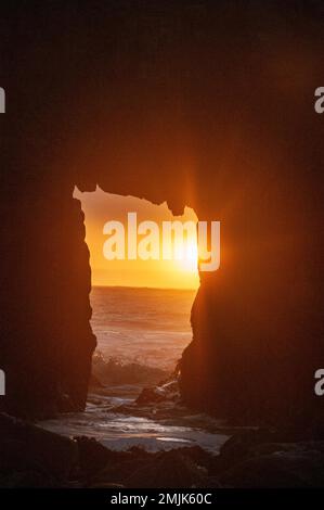 Particolare dell'arco Keyhole sulla spiaggia di Pfeiffer, con il sole che tramonta proprio dietro di essa. Foto Stock