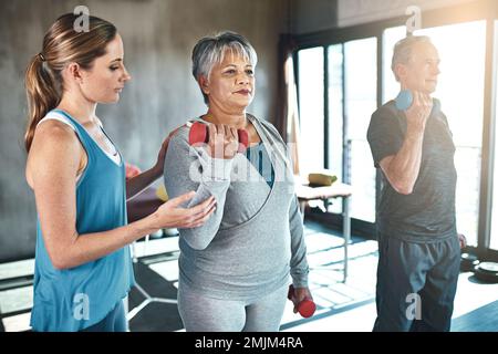È il momento di alzarsi e muoversi. un uomo anziano e una donna che usano i pesi con l'aiuto di un fisioterapista. Foto Stock
