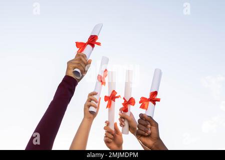 Laurea, mani e certificati in cielo per il successo, l'istruzione e il futuro. Gruppo di closeup, laureati e diploma al di fuori del premio di conoscenza Foto Stock