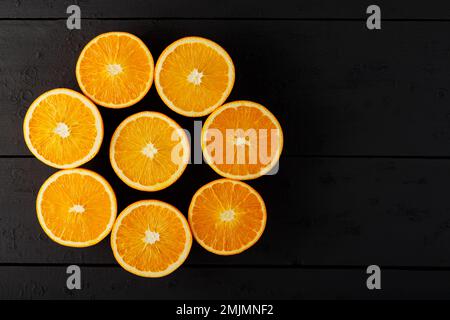 Luminose metà di arance su un tavolo di legno. Metà di arance succose su tavole nere Foto Stock
