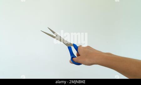 Aprire le forbici con la mano destra su sfondo bianco Foto Stock