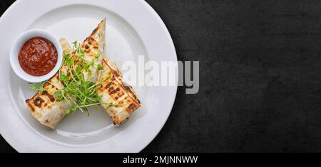 Pane pita con formaggio suluguni, salsa, microgreno, su piatto bianco, su cemento grigio. Banner Foto Stock