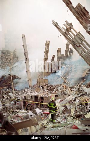 Un solo capo battaglione FDNY custodisce i resti di un motopompa antincendio mentre è circondato dalla devastazione mentre il sole sorge la mattina del 12th settembre, Foto Stock