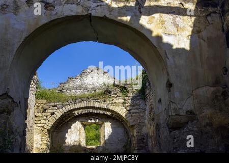 Rovine di un antico edificio contro il cielo blu. Soffitto collassato. Muratura, sala con volte ad arco in chiesa cristiana. L'erba cresce sulle pareti. Rashkov, Mo Foto Stock