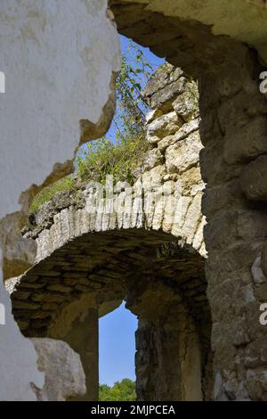 Rovine di un antico edificio contro il cielo blu. Soffitto collassato. Muratura, sala con volte ad arco in chiesa cristiana. L'erba cresce sulle pareti. Rashkov, Mo Foto Stock