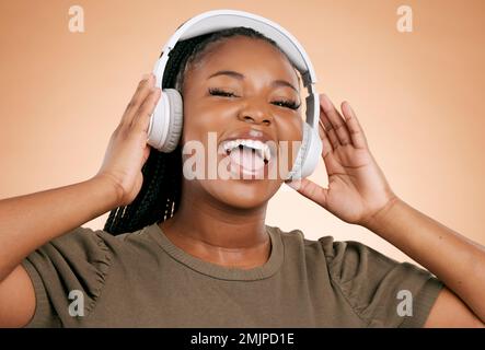 Cuffie, canto e ritratto di donna isolato su sfondo studio in salute mentale, energia e musica radio. Cantante, voce e gente di gen z nero Foto Stock