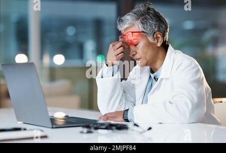 Notte, stress e mal di testa con il medico al computer portatile per il medico, il pensiero e la revisione delle scadenze. Burnout, responsabilità e salute mentale con anziani Foto Stock