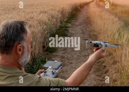 Uomo bearded che utilizza un drone con telecomando per realizzare foto e video, divertendosi con le nuove tendenze tecnologiche Foto Stock