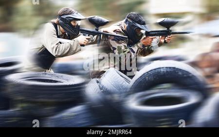 Paintball pistola, uomini e giochi bersaglio concorrenza o sport sfida in abiti militari per la battaglia. Soldati, esercito o persone che sparano armi di vernice in Foto Stock