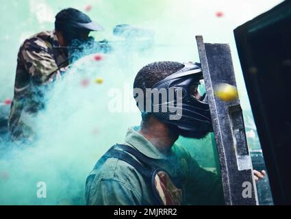 Paintball team, tiro insieme e gioco di guerra con scudo, maschera o strategia tattica per la sicurezza, concorrenza o concorso. Team all'aperto Foto Stock