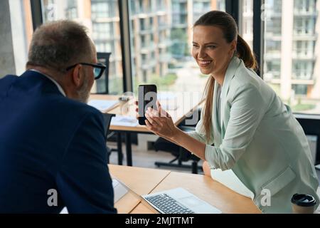 Imprenditore di successo che mostra lo schermo del telefono alla sua collega Foto Stock