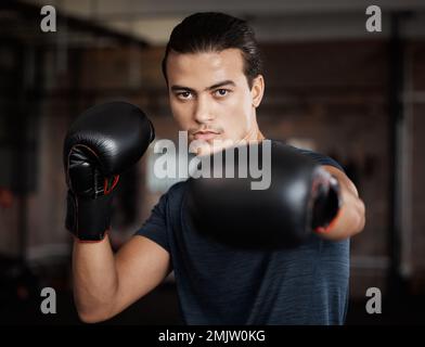 Ritratto, fitness e allenamento con un pugile di allenamento per una lotta o una competizione in palestra per lo sport. Salute, esercizio fisico e potere con un giovane maschio Foto Stock