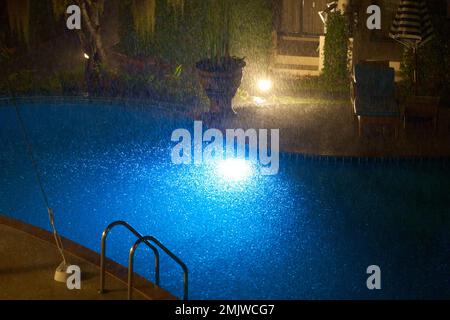 Un pesante acquazzone tropicale nel cortile dell'appartamento di notte allaga la piscina. Foto Stock