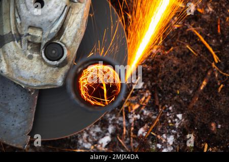 La smerigliatrice angolare funziona con un flusso luminoso di scintille, foto ravvicinata con messa a fuoco selettiva Foto Stock