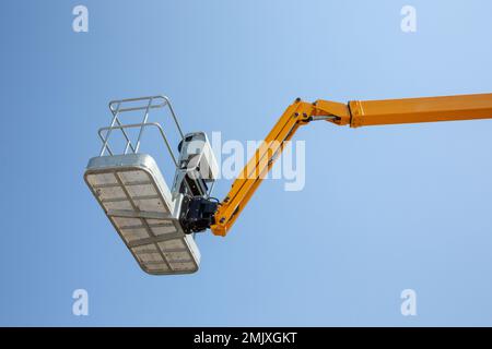 Gru da cantiere il braccio vuoto si solleva contro la piattaforma di lavoro blu Foto Stock