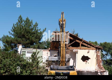 escavatore che lavora demolizione di casa vecchio edificio residenziale per la ricostruzione Foto Stock