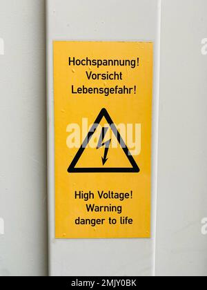 Cartello di avvertimento giallo con le parole: Alta tensione, attenzione pericolo di morte Foto Stock
