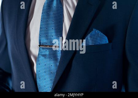 L'uomo in tuxedo blu corregge i bottoni sulla giacca. Dettagli matrimonio. Si può vedere la piazza blu cielo tasca, la clip cravatta e l'orologio sul polso Foto Stock