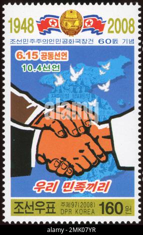 Francobollo nordcoreano del 2008 per commemorare il 60° anniversario della RPDC, con una stretta di mano e una mappa per la riunificazione coreana. Foto Stock