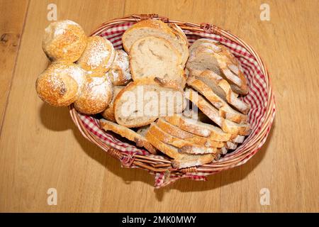 assortimento di pane affettato in un cesto su un tavolo di legno Foto Stock