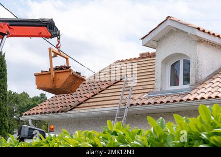 cambio di tegole sul tetto della casa con scarico alto sul cantiere Foto Stock