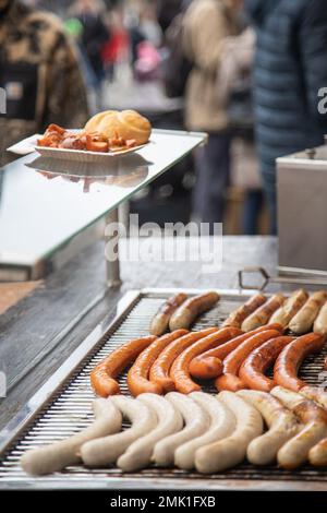 Varietà di salsicce tedesche sulla griglia di cottura di una stalla hot-dog Foto Stock