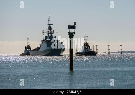 Una vista retroilluminata dei rimorchiatori Serco Marine che guidano la Royal Navy Ocean Patrol Vessel HMS Spey nel porto. Foto Stock