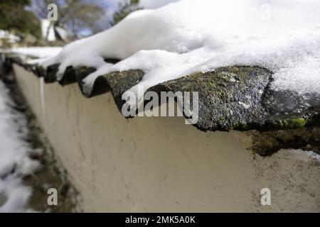 Tetto con ghiaccio e neve a casa, costruzione in ceramica, temporaneo Foto Stock