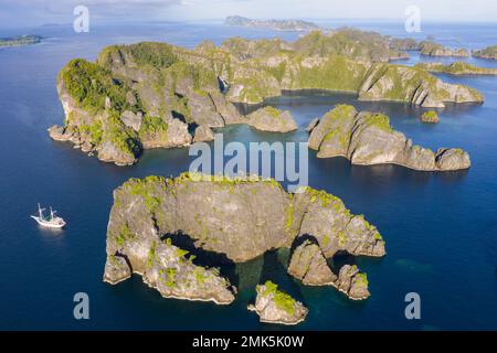 Le isole rocciose, composte di calcare, sorgono dal mare tropicale in Raja Ampat, Indonesia. Queste isole sono antiche barriere coralline innalzate. Foto Stock