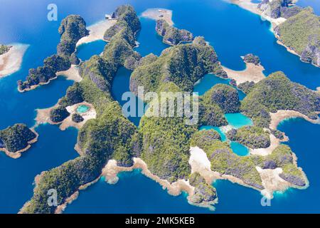 Le isole rocciose, composte di calcare, sorgono dal mare tropicale in Raja Ampat, Indonesia. Queste isole sono antiche barriere coralline innalzate. Foto Stock