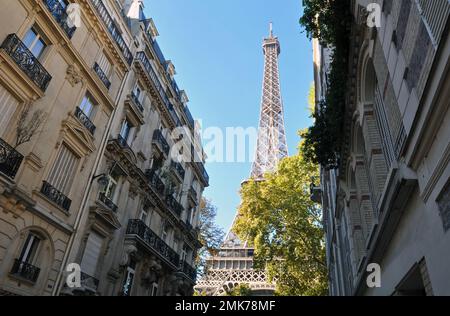 La Torre Eiffel sorge dietro edifici residenziali decorati alla fine di Rue de l'Université, nel 7th° arrondissement di Parigi. Foto Stock