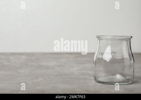 Vaso di vetro vuoto su tavolo grigio, spazio per il testo Foto Stock