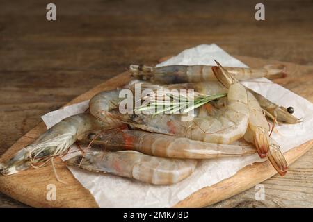 Gamberetti freschi crudi con rosmarino su tavola di legno Foto Stock